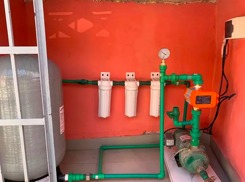 Water treatment setup with softener tank, three cartridge filters, pressure gauge and booster pump