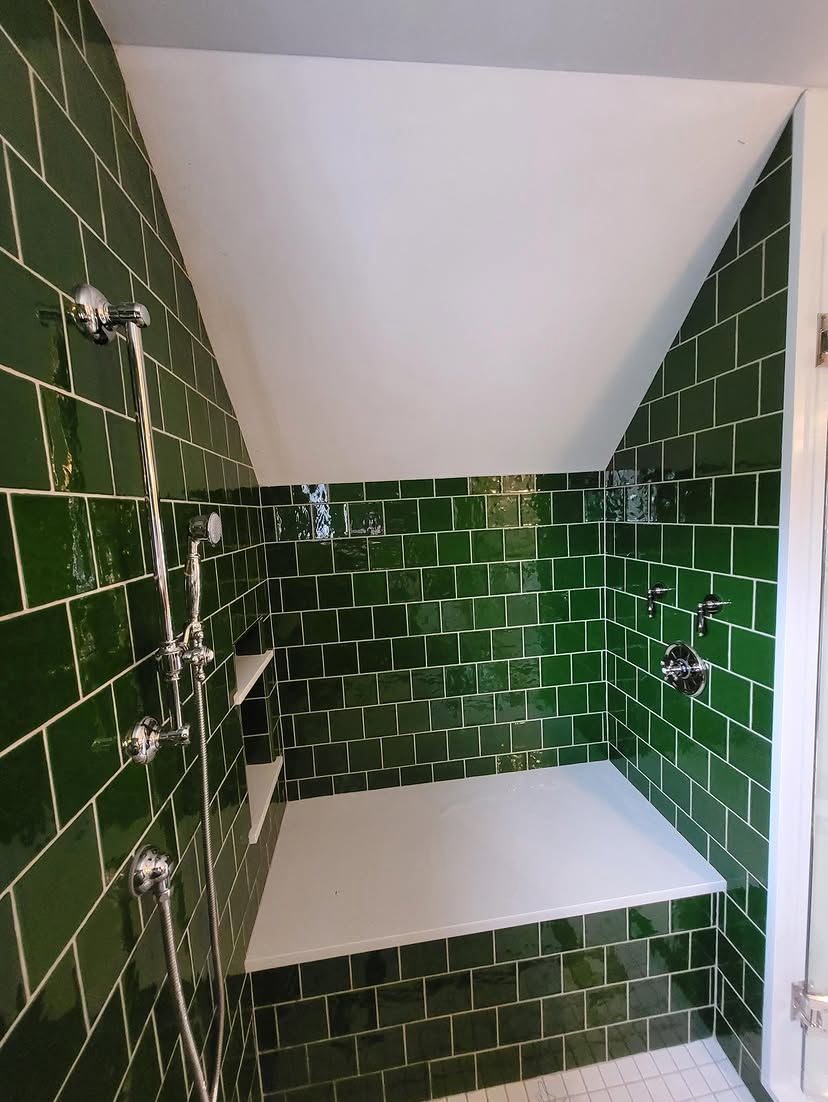Custom tiled walk-in shower with chrome rain head, handheld sprayer and built-in bench, plumbed under a sloped ceiling
